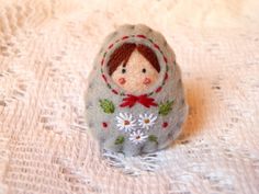 a small doll sitting on top of a white cloth covered table next to a doily