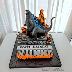 a godzilla birthday cake with orange sprinkles and black frosting on top