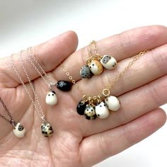 a person holding several different types of necklaces in their hand, including one with cats on them