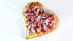 a heart shaped pastry with powdered sugar on top sits on a pink and white plate