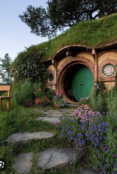 a hobbot house with a green door surrounded by flowers