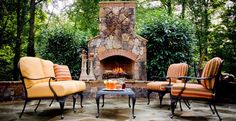 an outdoor fire place with chairs and tables