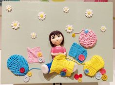 a doll sitting on top of a table next to some knitted items and flowers