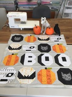 a quilted table runner with pumpkins on it and a sewing machine in the background