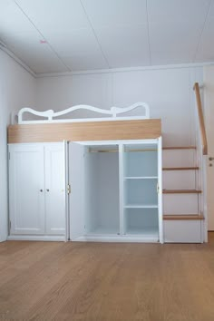 an empty room with a bed, stairs and cupboards on the floor in front of it