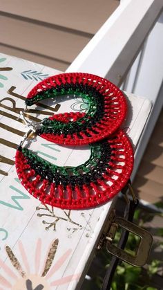 two red and green beaded wreaths sitting on top of a white chair outside