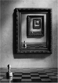 a black and white photo of a chess board in front of a framed painting on the wall