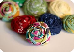 there are many different colors of fabric flowers on the table, one is multicolored