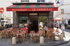 people sitting at tables in front of a restaurant