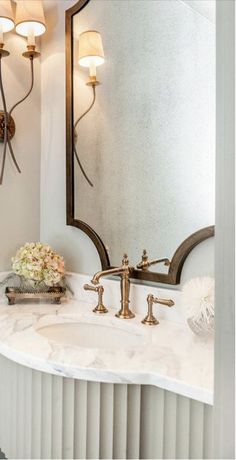 a bathroom sink sitting under a large mirror next to a wall mounted faucet