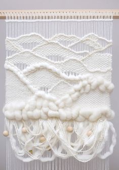 an art work with white yarn and wood beads