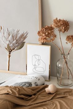 some flowers are in a glass vase on a table next to a framed photograph and an egg