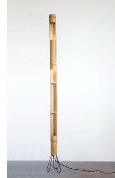 a floor lamp made out of bamboo sticks with two lights on each side and a cord connected to the base