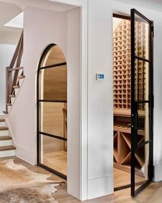 a wine cellar in the middle of a room with stairs leading up to it's second floor