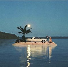 two people standing on an island in the middle of water with a car parked next to it