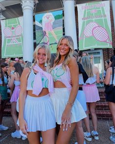 two young women standing next to each other in front of a building with tennis banners