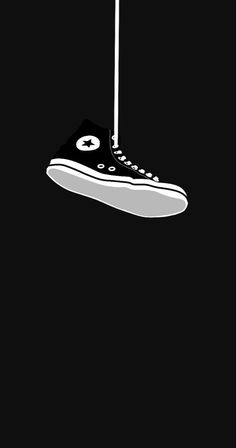 a black and white image of a shoe hanging from a string with an eyeball on it