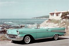 an old car is parked on the side of the road near the water and rocks