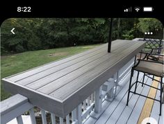 an outdoor deck with bar stools and table on it in the middle of a yard