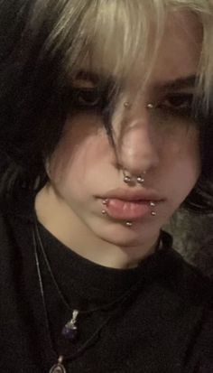 a woman with piercings on her nose and neck is looking at the camera while wearing a black shirt