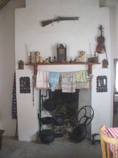 an old fashioned fireplace with pots and pans on the mantel in front of it