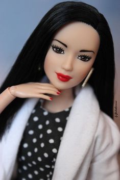 a close up of a doll with long black hair and red lipstick on her face