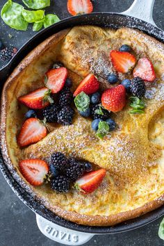 an omelet with berries and powdered sugar on top is ready to be eaten