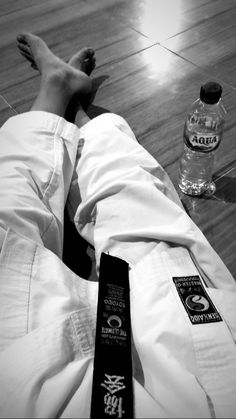 a person laying on the floor next to a bottle of water and an empty tie