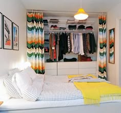 a bedroom with a bed, closet and clothes on hangers