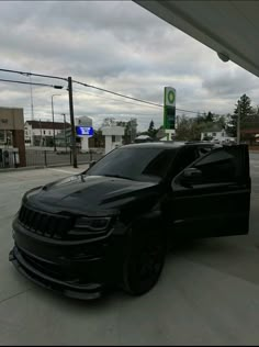 a black car is parked in front of a gas station with no one around it