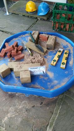 a child's sand and water table with construction tools in it on the ground