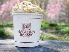 a white cup filled with food sitting on top of a cement ground next to trees