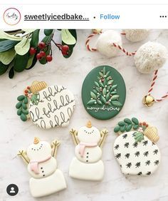 christmas cookies decorated with frosting and decorations on a marble countertop next to greenery