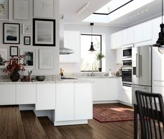 a kitchen with white cabinets and pictures on the wall