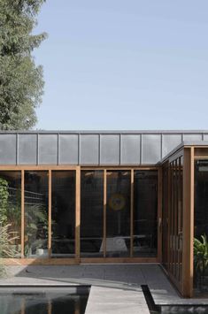 an outdoor room with glass walls and wood trimming on the roof, surrounded by water