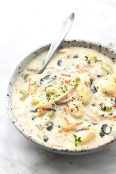 a white bowl filled with soup on top of a table next to a silver spoon