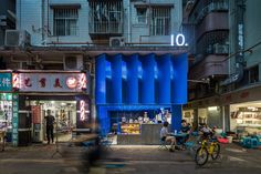 people are sitting at tables in front of a building with blue columns on the side