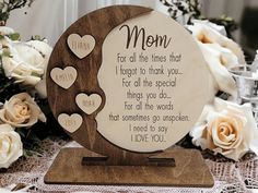 a mother's day plaque with hearts on it and flowers in the background, including roses