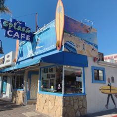 a building with a surfboard on the top of it's roof that says splash cafe