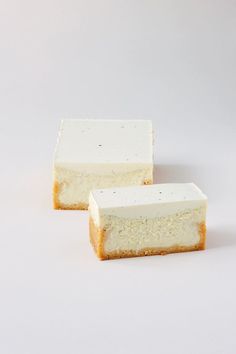 two pieces of cheesecake sitting next to each other on a white surface with black speckles