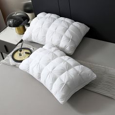 a bed with two pillows on top of it and a clock in the middle next to it