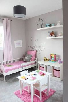 a child's room with two beds, a table and toys on the floor