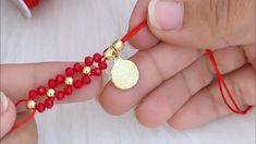 two hands holding red beads and a gold pendant