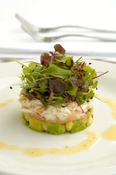 a white plate topped with a salad covered in veggies and garnish