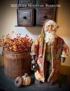 a statue of santa claus next to a potted plant and some pumpkins on a table