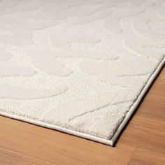 a white area rug on top of a wooden floor in a living room or bedroom