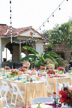 an outdoor event with tables and chairs covered in tablecloths, flowers and candles