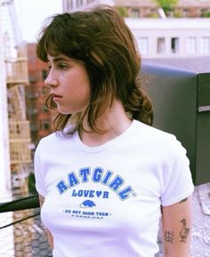 a woman standing on top of a roof with her hand in her pocket and looking off to the side