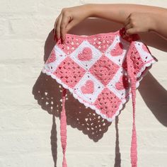 a crocheted pink and white purse being held by a woman's hand