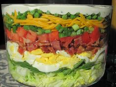 a layered salad in a glass bowl on a table